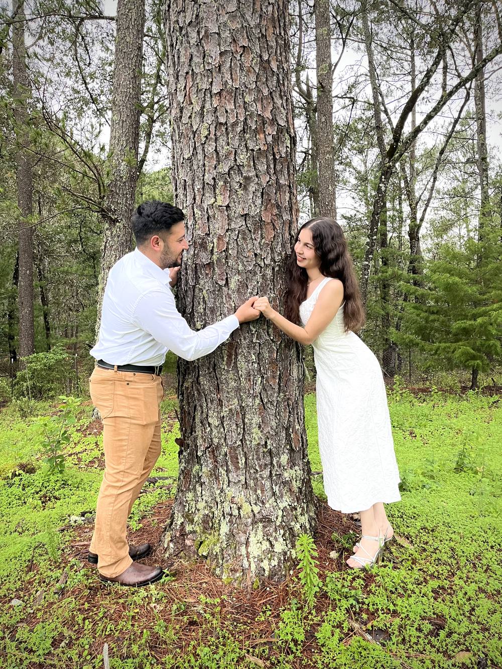 Tania y Manuel tomados de las manos alrededor de un pino